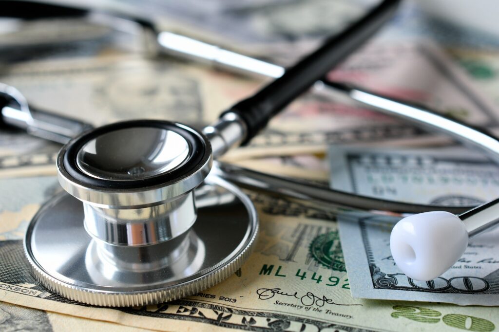 A stethoscope laying on money - Medical costs